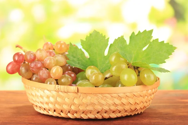 Ripe sweet grape in basket on wooden table, on nature background — Stock Photo, Image