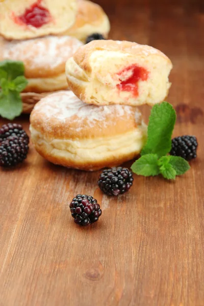 Leckere Donuts mit Beeren auf Holztisch — Stockfoto