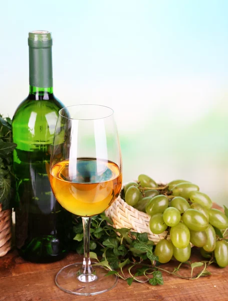 Спелый зеленый и фиолетовый виноград в корзине с вином на деревянном столе на ярком фоне — стоковое фото