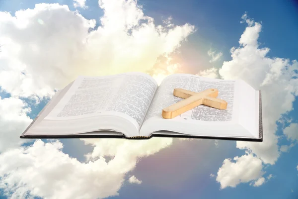 Bíblia Sagrada e cruz de madeira no fundo do céu — Fotografia de Stock