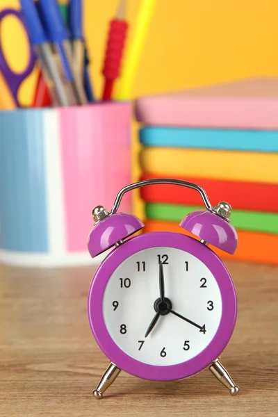 黄色の背景にテーブルの上の紫色の目覚まし時計 — ストック写真