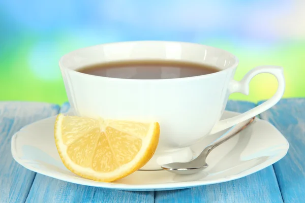 Filiżanka herbaty z cytryną na stole na niebieskim tle — Zdjęcie stockowe