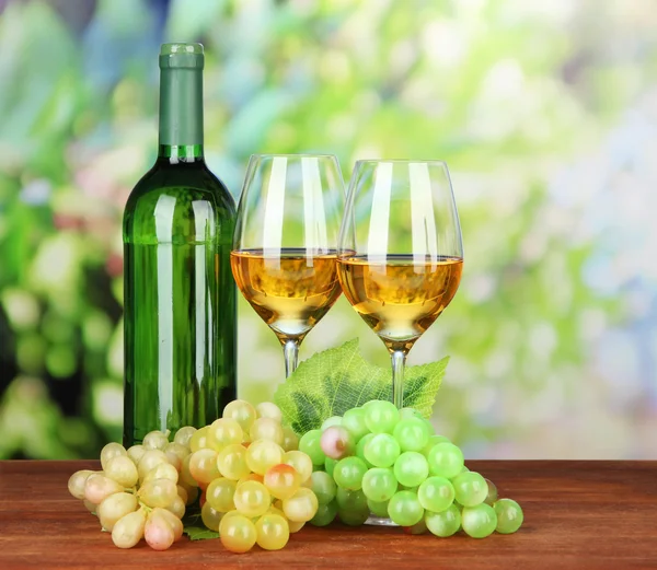 Ripe grapes, bottle and glasses of wine, on bright background — Stock Photo, Image