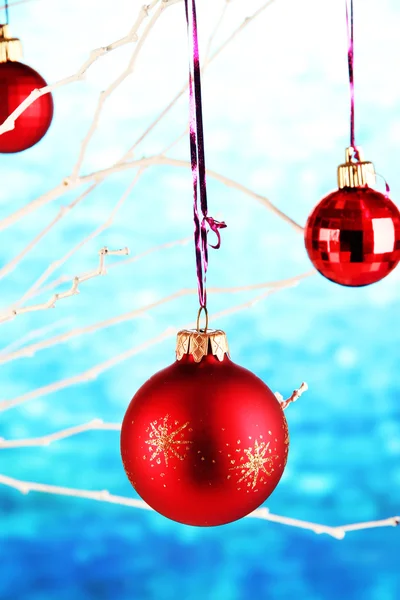 Juguetes de Navidad colgando en la rama sobre fondo azul —  Fotos de Stock