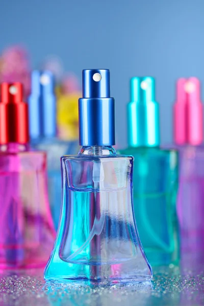 Жіночі парфуми в красивих пляшках і квітах на синьому фоні — стокове фото