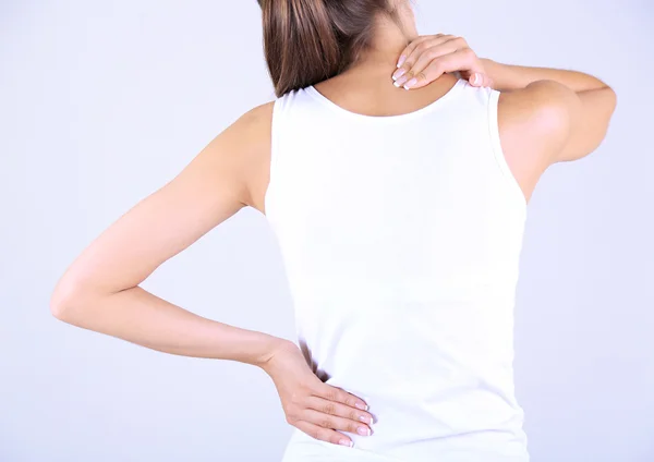 Junges Mädchen und Schmerzen im Nacken grauen Hintergrund — Stockfoto