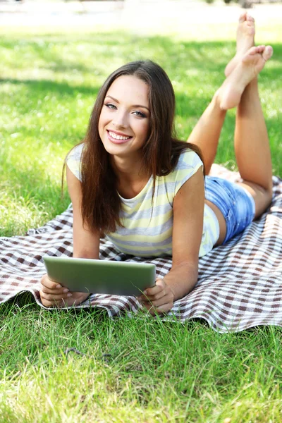 Vacker ung flicka med tablett i park — Stockfoto