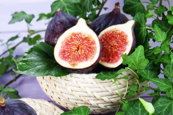 Ripe figs in basket in leaves on wooden table close-up — Stock Photo, Image