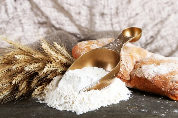 The wholemeal flour in scoop on wooden table on sackcloth background — Stock Photo, Image