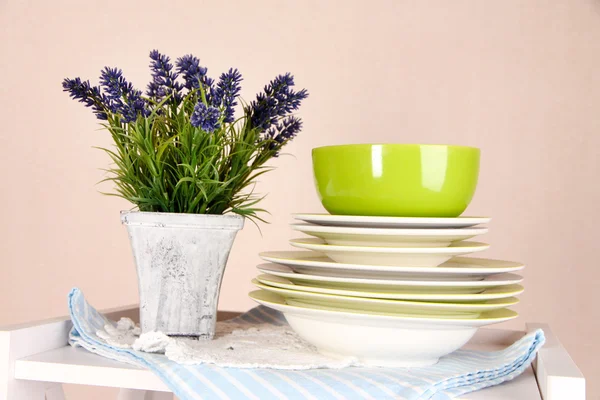 Prateleiras brancas bonitas com utensílios de mesa e decoração, no fundo da parede de cor, close-up — Fotografia de Stock