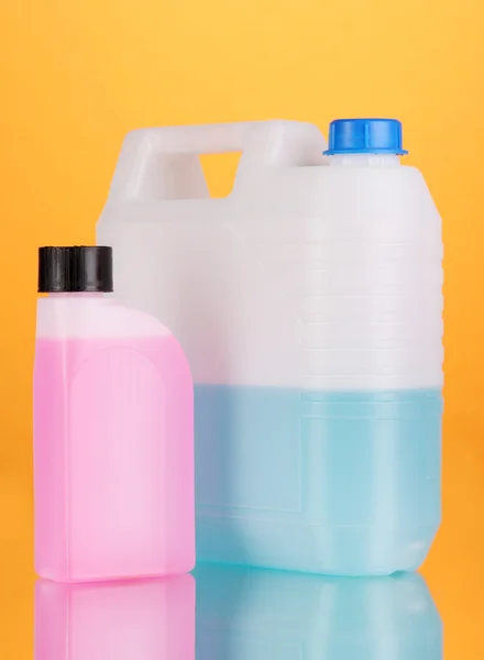 Blaue und rosa Flüssigkeiten für Autos in Kanistern auf orangefarbenem Hintergrund — Stockfoto
