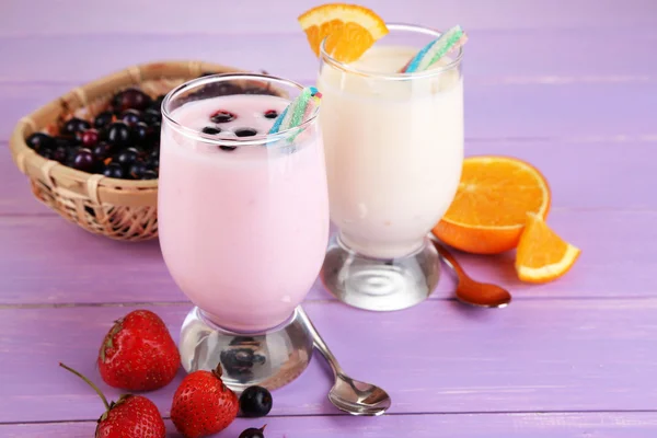 Heerlijke melk schudt met sinaasappel en blackberry op houten tafel close-up — Stockfoto