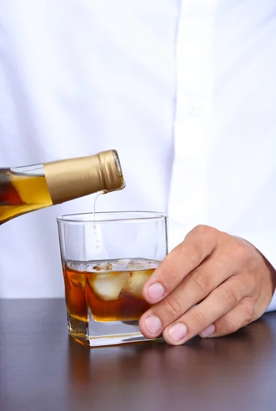 Bartender is pouring whiskey into glass — Stock Photo, Image