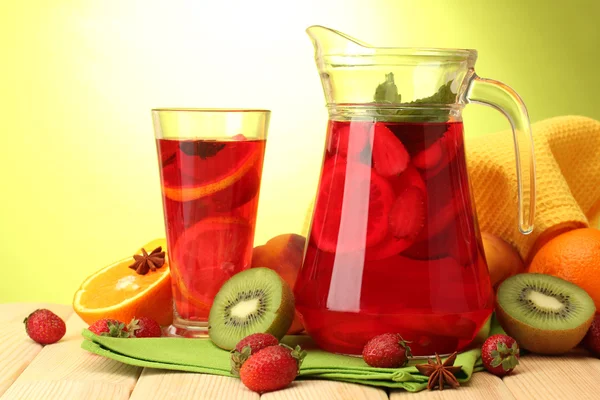 Sangria in vaso e vetro con frutta, su tavola di legno, su fondo verde — Foto Stock