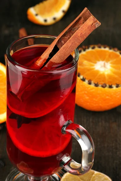 Duftender Glühwein im Glas mit Gewürzen und Orangen auf Holztisch — Stockfoto