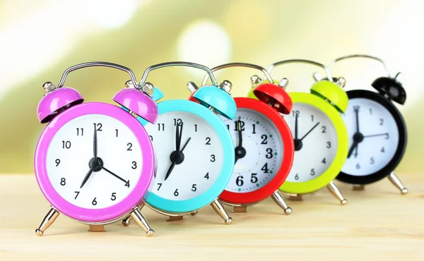 Colorful alarm clocks on table on light background — Stock Photo, Image