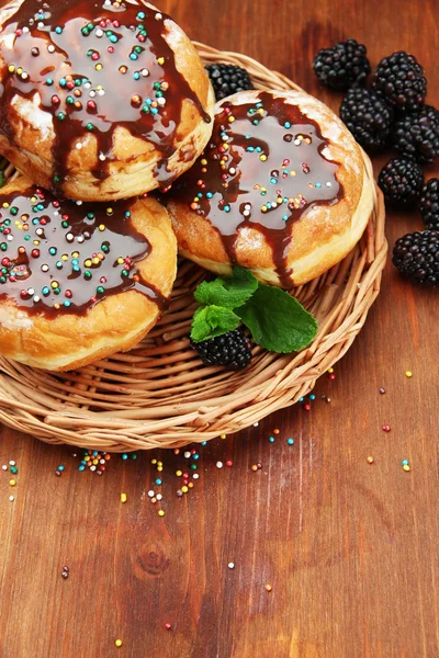 Smakelijke donuts met chocolade en bessen op houten tafel — Stockfoto