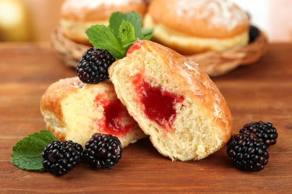 Tasty donuts with berries on wooden table — Stock Photo, Image