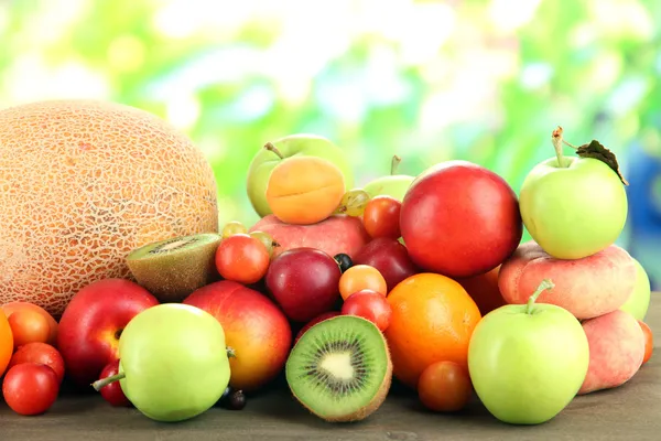 Surtido de frutas jugosas, sobre mesa de madera, sobre fondo brillante — Foto de Stock