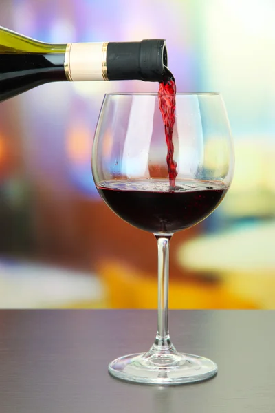 Vin rouge versé dans un verre à vin, sur fond lumineux — Photo