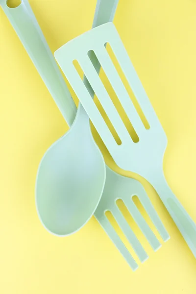 Plastic kitchen utensils on yellow background — Stock Photo, Image