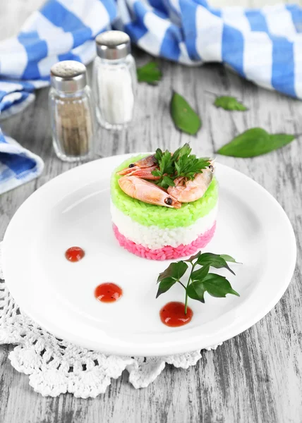 Arroz colorido na placa perto do guardanapo na mesa de madeira — Fotografia de Stock