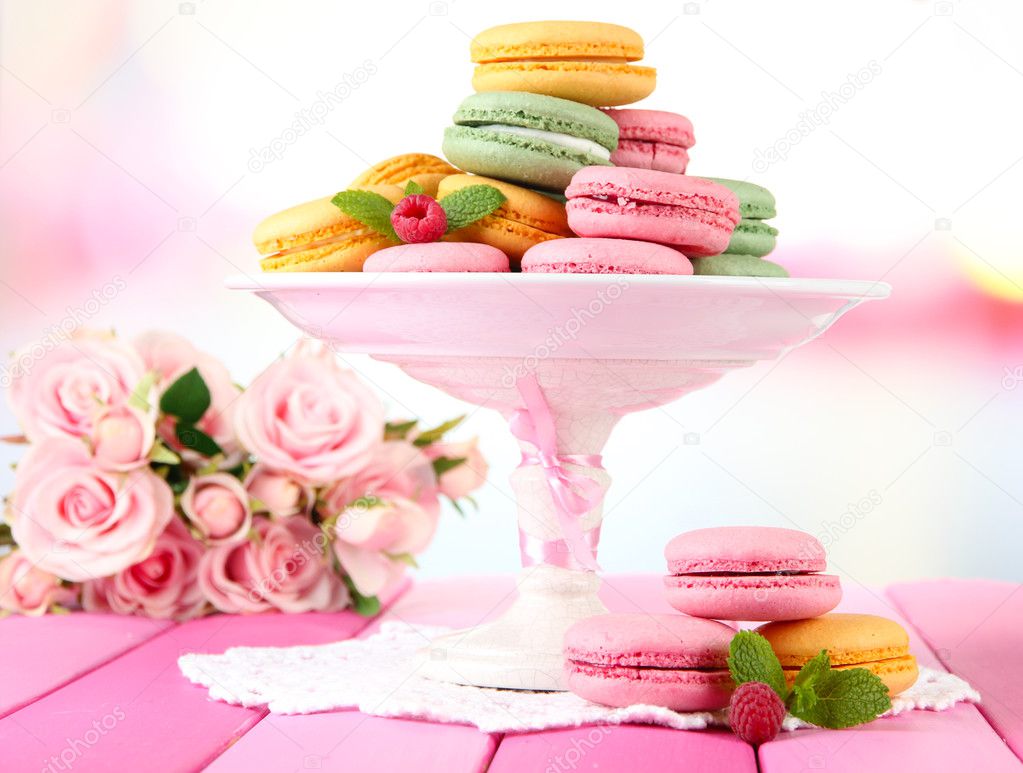 Gentle macaroons in vase on table on light background