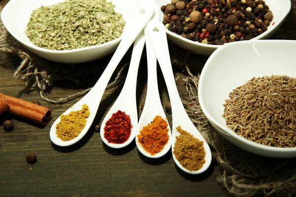 Assortment of spices in white spoons and bowls, on wooden background — Stock Photo, Image