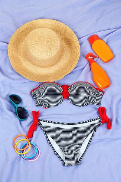 Swimsuit and beach items on purple background — Stock Photo, Image