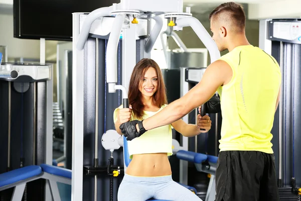 Chica y entrenador participan en simulador en el gimnasio — Foto de Stock