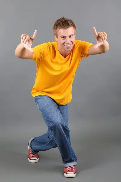 Schöner junger Mann tanzt auf grauem Hintergrund — Stockfoto