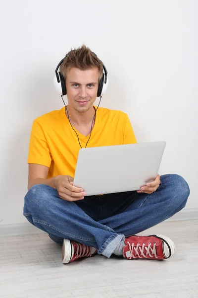 Красивый молодой человек слушает музыку на сером фоне — стоковое фото