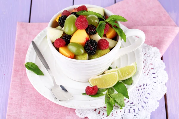 Salada de frutas em xícara em guardanapo em mesa de madeira — Fotografia de Stock