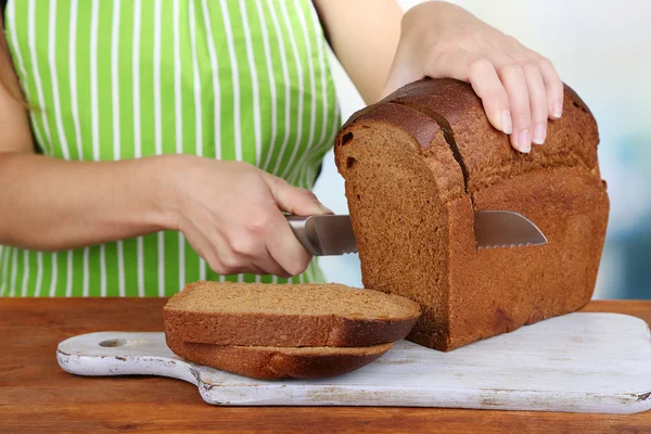 Cięcia chleba na desce na drewnianym stole na naturalne tło — Zdjęcie stockowe