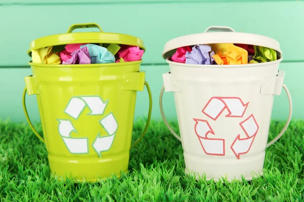Papeleras de reciclaje sobre hierba verde sobre fondo de madera de color —  Fotos de Stock