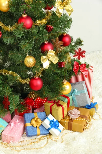 Decorated Christmas tree with gifts on grey wall background — Stock Photo, Image