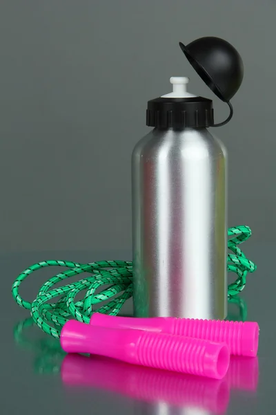 Sports bottle and skipping rope on grey background — Stock Photo, Image