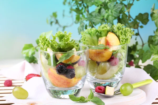 Fruitsalade in bril, op houten tafel, op lichte achtergrond — Stockfoto
