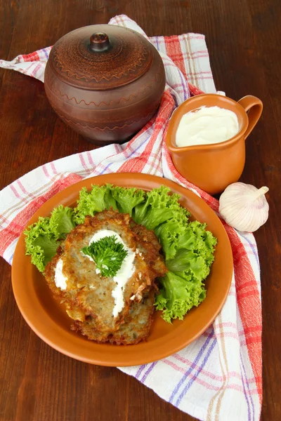 Potato pancakes in pot, on wooden background — Stock Photo, Image