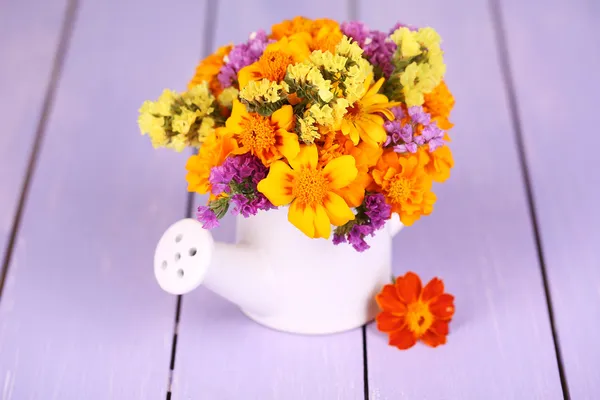 Ramillete de flores de caléndula en una regadera sobre una mesa de madera — Foto de Stock