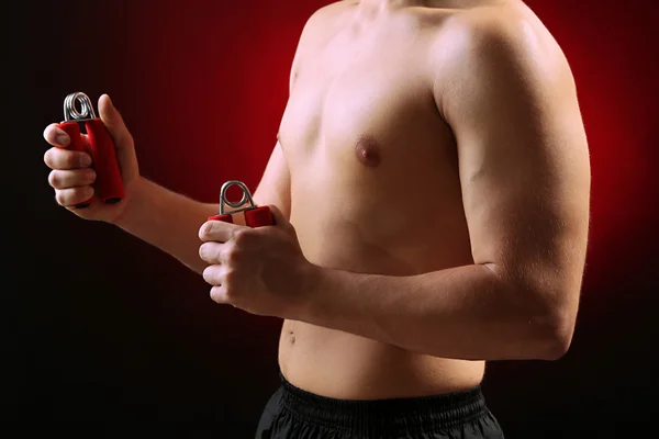 Joven deportista musculoso guapo con expansores, sobre fondo oscuro — Foto de Stock