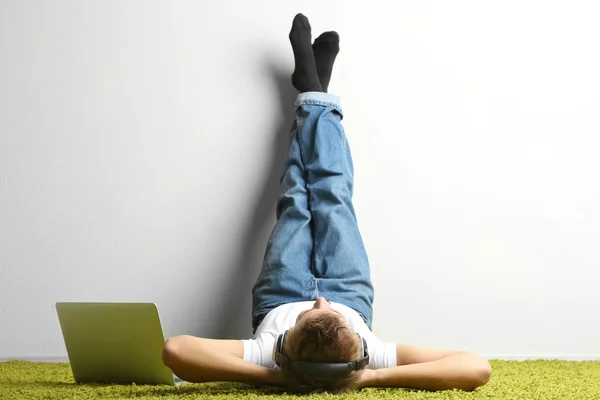 Jovem relaxando no tapete e ouvindo música — Fotografia de Stock