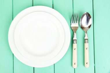 Plate and cutlery on wooden table close-up