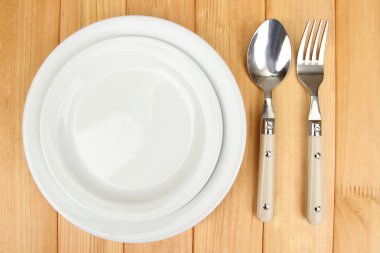 Plate and cutlery on wooden table close-up