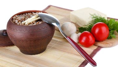 Buckwheat in pot with butter and vegetables isolated on white