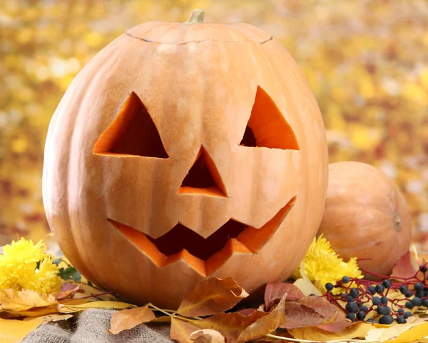 Halloween pumpkins and autumn leaves, on yellow background — Stock Photo, Image