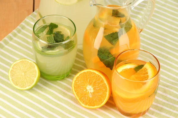 Limonada de laranja e limão em jarros e copos em close-up de mesa de madeira — Fotografia de Stock