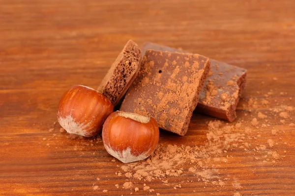 Apróra vágott csokoládé a kakaó, a fából készült háttér — Stock Fotó