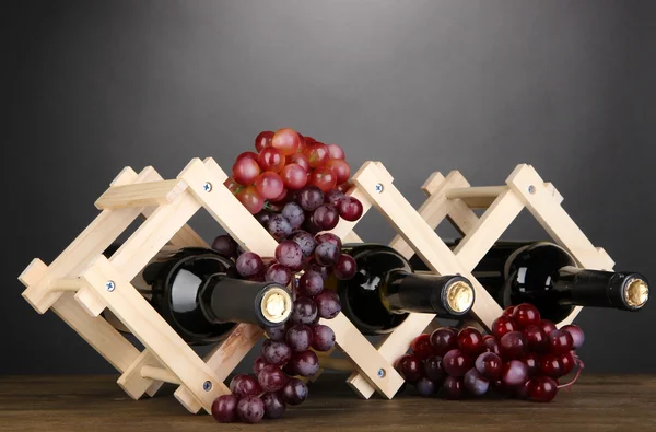 Botellas de vino colocadas sobre soporte de madera sobre fondo gris — Foto de Stock