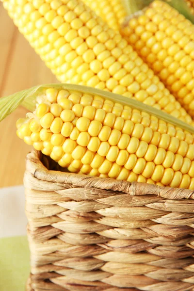 Crude corns in basket on napkin on wooden table — Stock Photo, Image